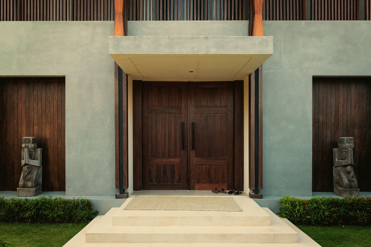 Villa entrance with timber doors and two stone statues