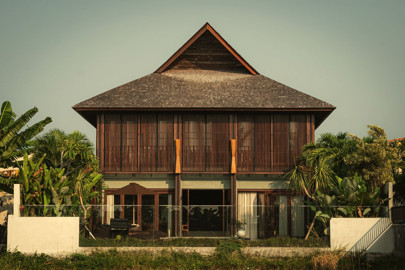 The villa seen from the rice fields, beneath its tall shingled roof