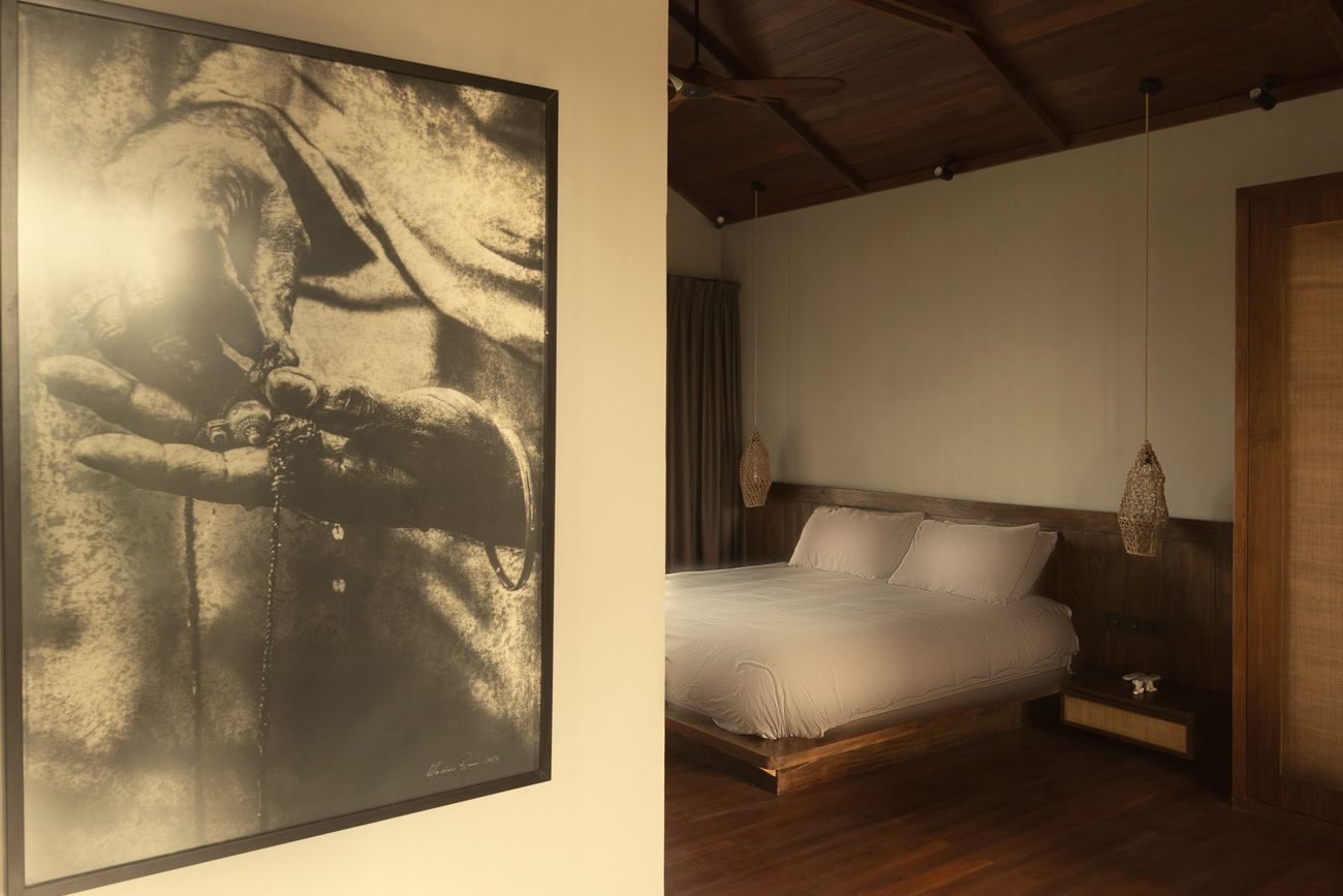 Bedroom with a pitched ironwood ceiling and a large artwork of hands